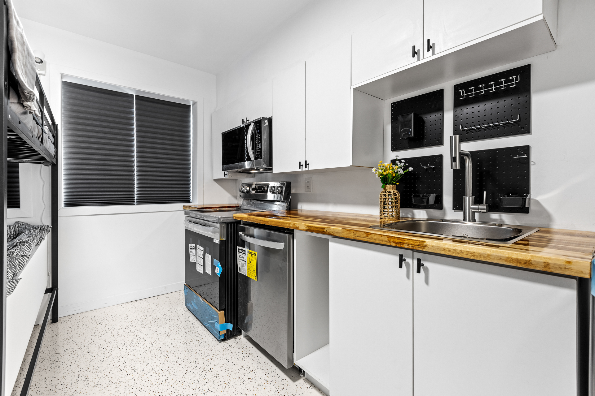 Unit 09 kitchen: full-size range, dishwasher, acacia butcherblock counter, integrated sink, and LG WashCombo lined up on a single wall.
